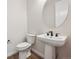 Half bathroom featuring a pedestal sink, stylish dark fixtures, and modern finishes at 5583 Riverbend Ave, Firestone, CO 80504