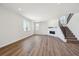 Open living room featuring wood floors, a fireplace, and a staircase with iron railing at 5583 Riverbend Ave, Firestone, CO 80504