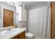 Bright bathroom featuring a shower-tub combo, a white toilet, and vanity with wood-look cabinets at 1801 Aspen St, Fort Lupton, CO 80621