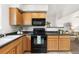 Kitchen showcasing wooden cabinets and black appliances with view to the living room at 5444 Zephyr St # 203, Arvada, CO 80002