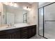 Modern bathroom features a double sink vanity with dark cabinets and a glass-enclosed shower at 888 S Valentia St # 101, Denver, CO 80247