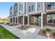 A modern townhome boasts brick accents, stylish gray siding, a welcoming covered porch, and lush landscaping at 888 S Valentia St # 101, Denver, CO 80247