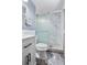Modern bathroom with gray tile flooring, a frosted glass-enclosed shower, and a white vanity with dark hardware at 140 Lane Ct, Fort Lupton, CO 80621