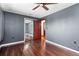 Bedroom with hardwood flooring, modern ceiling fan, and gray walls with a walk in closet featuring mirrored doors at 140 Lane Ct, Fort Lupton, CO 80621