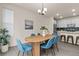 Bright dining area adjacent to modern kitchen features wood table, blue chairs, and contemporary lighting at 4343 S Nepal Ct, Centennial, CO 80015