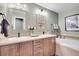 Bathroom featuring double sinks with stylish mirrors and a luxurious soaking tub at 9218 Viaggio Way, Highlands Ranch, CO 80126