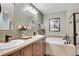 Bathroom featuring double sinks with wood cabinets, stylish mirrors, and a luxurious soaking tub at 9218 Viaggio Way, Highlands Ranch, CO 80126