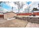 Backyard featuring a shed with a garage door, tiered landscaping, and a red fence at 4440 W Hayward Pl, Denver, CO 80212