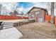 Brick home backyard featuring a concrete patio with outdoor furniture, a red fence, and retaining wall at 4440 W Hayward Pl, Denver, CO 80212