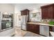 Cozy kitchen features stainless steel appliances, dark wood cabinets, and a stylish tile backsplash at 4440 W Hayward Pl, Denver, CO 80212