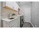 Laundry room featuring modern appliances, stylish wallpaper, ample storage, and a sleek countertop at 5746 Aspen Creek Dr, Broomfield, CO 80020