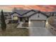 Stunning sunset view of home with a two-car garage, manicured lawn, and elegant stone accents at 16500 Crosby Dr, Broomfield, CO 80023