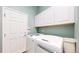Well-lit laundry room featuring white cabinets and modern front-loading washer and dryer at 16500 Crosby Dr, Broomfield, CO 80023