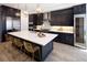 Stylish kitchen featuring dark cabinets, stainless steel appliances, a center island with seating, and elegant lighting fixtures at 6123 Chester Way, Denver, CO 80238