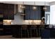 Modern kitchen featuring dark cabinets, a white backsplash, and a center island with seating and contemporary pendant lights at 6123 Chester Way, Denver, CO 80238
