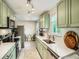 Bright kitchen featuring sage-green cabinets, modern appliances, and a cozy breakfast nook with natural light at 6346 Fenton St, Arvada, CO 80003