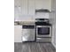 Close-up of stainless steel dishwasher and oven under a vent with white cabinets and tile backsplash at 1304 S Parker Rd # 359, Denver, CO 80231