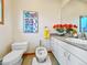 A quaint bathroom featuring a bidet, toilet and vanity with orange flowers and bright poster at 857 Pawnee Trl, Castle Rock, CO 80108