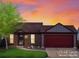 Charming brick home featuring a two-car garage, landscaped front yard, and warm sunset lighting at 11256 W 104Th Ave, Broomfield, CO 80021