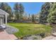 Expansive backyard featuring lush lawn, mature trees, and a brick patio at 7946 S Pennsylvania Ct, Littleton, CO 80122