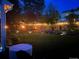 Nighttime backyard scene highlighting a lush green lawn, ambient lighting, and comfortable seating at 7946 S Pennsylvania Ct, Littleton, CO 80122