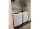 Modern laundry room with white washer and dryer, shelving, and wooden floor at 10457 W Hampden Ave # 104, Lakewood, CO 80227