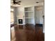Open living area with a fireplace, built-in shelving, and a door leading to a patio, enhanced by dark wood floors at 10457 W Hampden Ave # 104, Lakewood, CO 80227