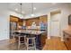 A well-lit kitchen with wood floors, featuring an island with barstools, stainless steel appliances, and wood cabinetry at 9580 E 5Th Ave, Denver, CO 80230