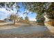 A view of the property featuring a gravel landscape, a wooden fence, mature trees, and blue sky at 9783 Zephyr Dr, Broomfield, CO 80021