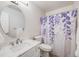 Bathroom with a white vanity, oval mirror, toilet, and shower with patterned curtain at 3964 S Yosemite St, Denver, CO 80237