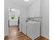 Bright laundry room featuring a washer and dryer, with wood floors and additional storage cabinets at 4125 Pierce St, Wheat Ridge, CO 80033