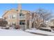 Charming two-story townhouse with tan siding and a cozy balcony, surrounded by a snowy landscape at 3847 Mossy Rock Dr # 104, Highlands Ranch, CO 80126