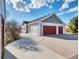 Charming home features a three-car garage with red doors, gray siding, and a well-maintained concrete driveway at 56450 E 40Th Ave, Strasburg, CO 80136