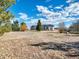 Home in a rural setting, featuring a well-manicured lawn and mature trees against a clear blue sky with fluffy clouds at 56450 E 40Th Ave, Strasburg, CO 80136