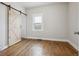 Bedroom features hardwood floors, a sliding barn door, and natural light at 4046 S Bannock St, Englewood, CO 80110