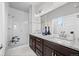 Bathroom featuring double sinks, granite countertops, dark cabinets, and large walk-in shower at 6700 Clay St, Denver, CO 80221