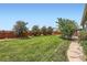 Manicured backyard with a lush lawn, stone walkway, and a full privacy fence at 5328 Potentilla St, Brighton, CO 80601