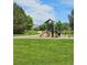 Community playground with slide, climbing structure, and walking path surrounded by mature trees and green space at 5328 Potentilla St, Brighton, CO 80601