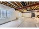 Unfinished basement with exposed beams, white walls, and concrete floors with natural light at 12631 Glencoe St, Thornton, CO 80241
