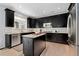 Kitchen features black cabinetry, a stainless steel dishwasher, and stone countertops at 4545 S Monaco St # 328, Denver, CO 80237