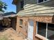 Exterior side view of backyard featuring brick and peeling paint with a door and window at 12252 Elmendorf Pl, Denver, CO 80239