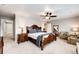 Well-lit main bedroom with a large bed, ceiling fan, sitting area, and neutral colored carpet at 17955 Sky Pilot Ave, Parker, CO 80134