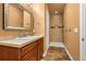 Bathroom featuring a framed mirror, wood vanity, and a glass-enclosed shower at 17533 W 60Th Ln, Arvada, CO 80403