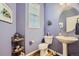 Charming powder room with pedestal sink, round mirror, and seashell accents against purple walls at 6268 Pike Ct # D, Arvada, CO 80403