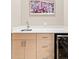 Convenient wet bar with light wood cabinets, stainless steel sink, wine fridge, and modern hardware at 3515 S Ogden St, Englewood, CO 80113
