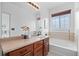 Relaxing bathroom features a soaking tub, wooden blinds, and a vanity with wood cabinets at 101 Granby Way # B, Aurora, CO 80011