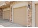 Attached beige garages with brick columns and exterior lighting at 101 Granby Way # B, Aurora, CO 80011