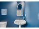 Blue powder room featuring a pedestal sink, gold faucet, and an elongated oval mirror above at 101 Granby Way # B, Aurora, CO 80011