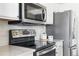 Close up of modern range and microwave with stainless appliances and neutral tile backsplash at 5763 N Gibralter Way # 2-108, Aurora, CO 80019