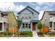 Inviting blue two-story home featuring a welcoming orange front door, manicured landscaping, and natural light at 10025 E 63Rd Ave, Denver, CO 80238